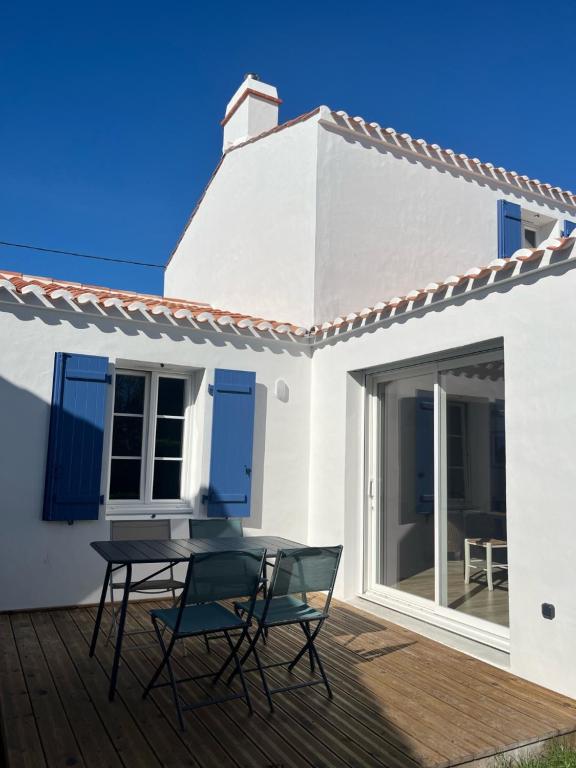 a patio with a table and chairs on a deck at maison 6-8 personnes, 300m de la plage in La Guérinière