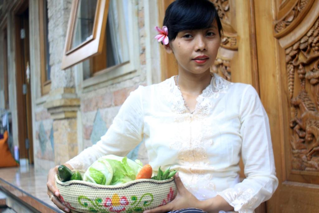 a woman holding a basket of fruits and vegetables at The Reinhold Guesthouse Bali in Kerobokan