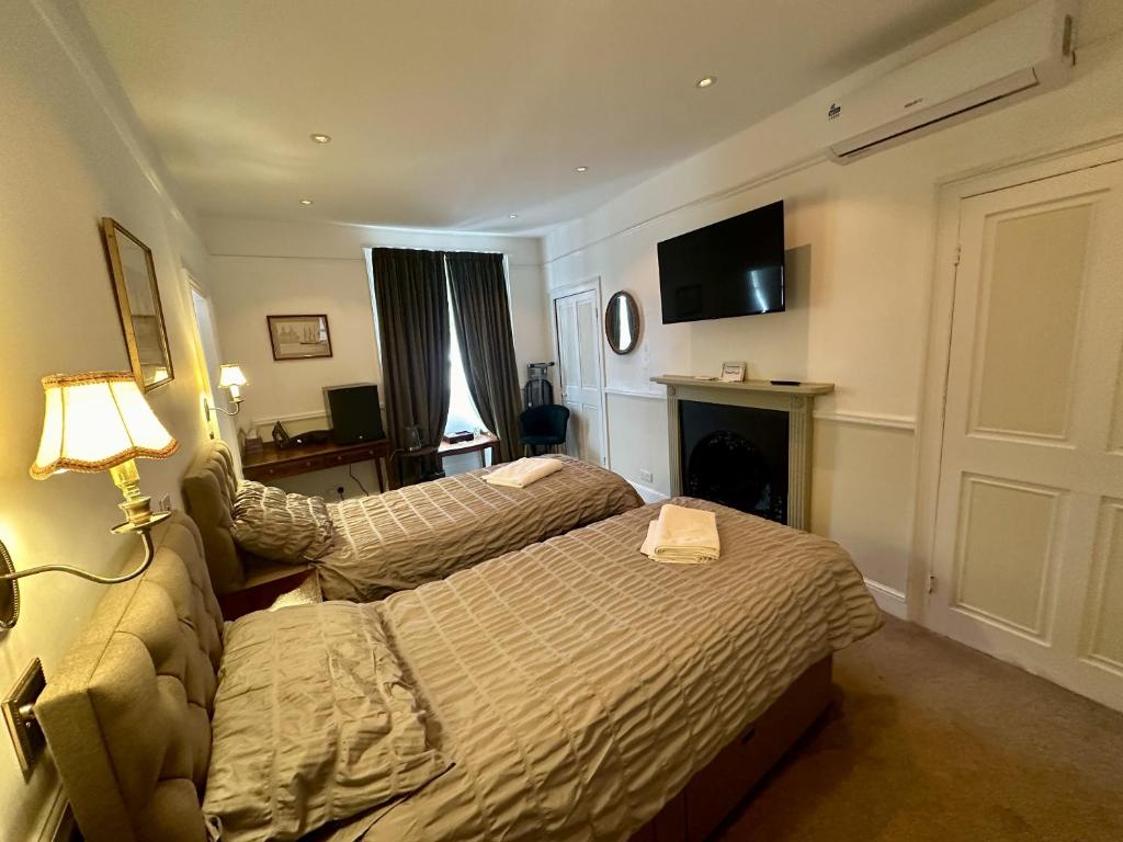 a hotel room with two beds and a fireplace at The Dulwich in Cheltenham