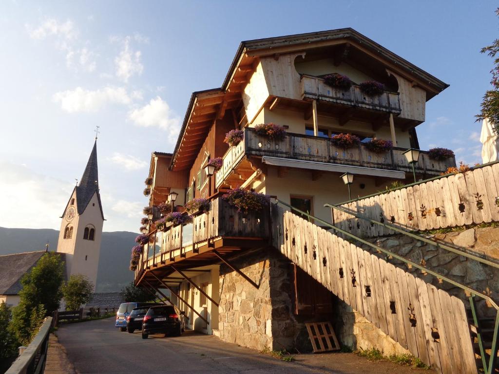 ein Gebäude mit Balkonen und eine Kirche im Hintergrund in der Unterkunft Gasthaus Dorfberg in Kartitsch