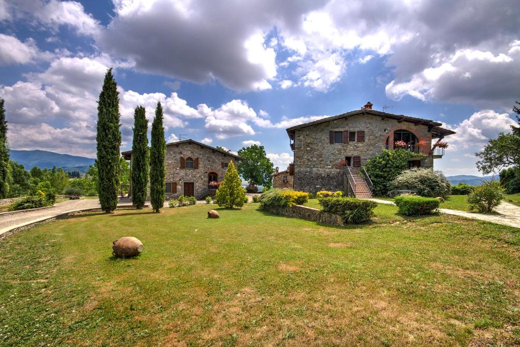 プラトヴェッキオにあるBorgo Romenaの木の植わる庭の大きな石造りの家