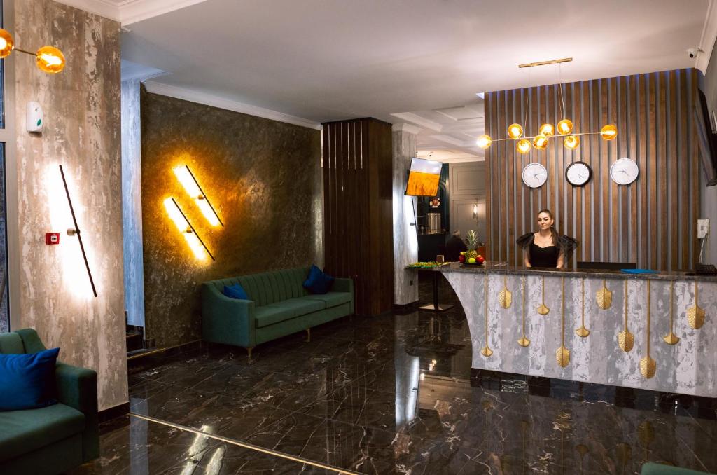 a woman standing behind a bar in a hotel lobby at Grand Magistral in Qarasū