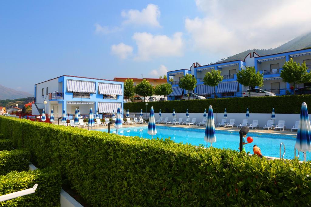 a resort with a swimming pool with blue umbrellas at Residence Soleluna in Praia a Mare