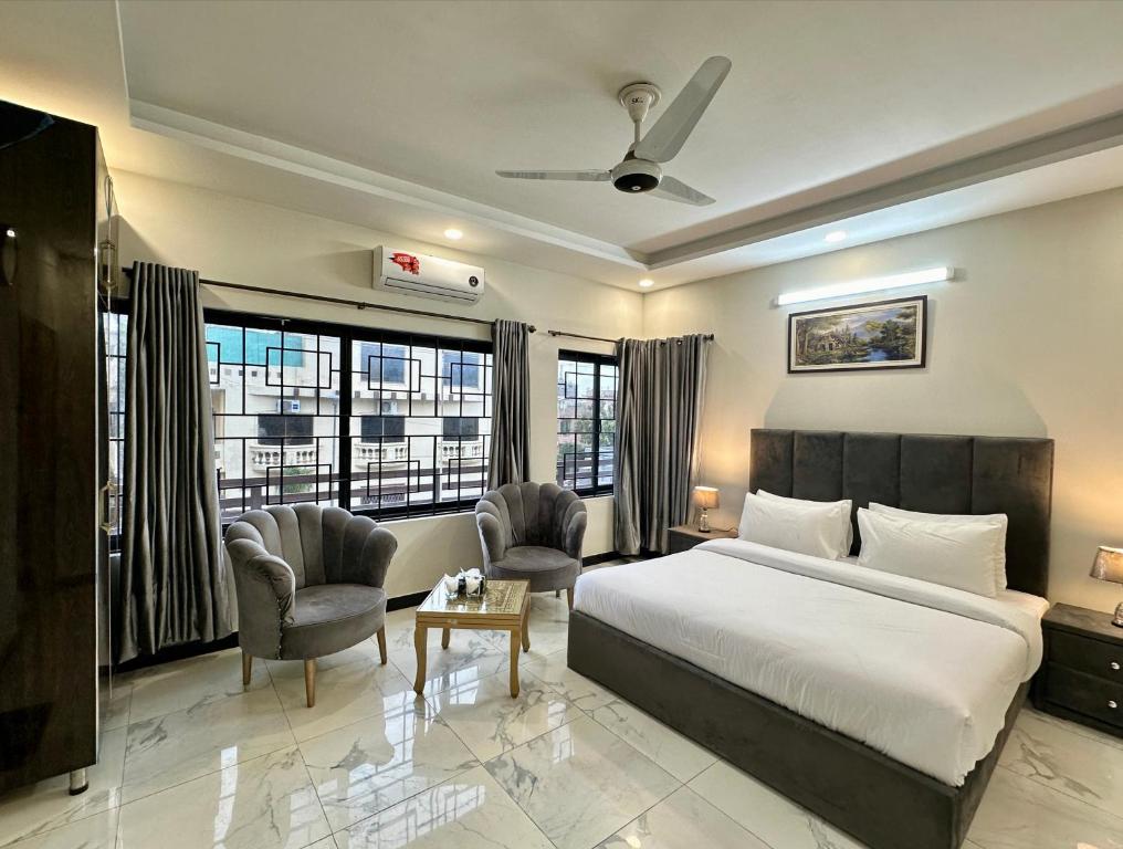 a hotel room with a bed and two chairs at Western Lodge Guest House Islamabad in Islamabad