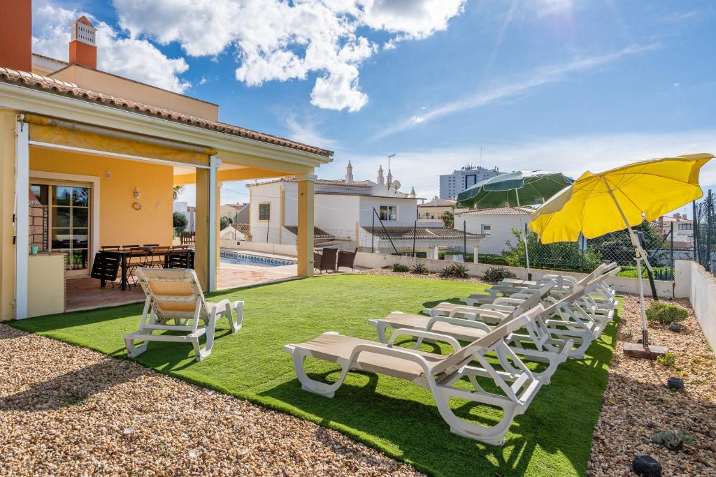 una fila di sedie a sdraio e un ombrellone su un prato di Villa Alvor ad Alvor