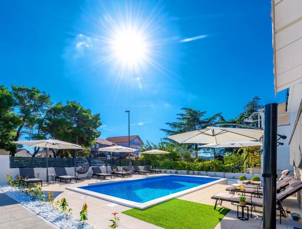 une piscine avec chaises et parasols à côté d'un bâtiment dans l'établissement Apartments Sunny Sky, à Vodice