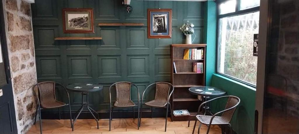 a green wall with chairs and tables in a room at St aubyn arms Hotel in Praze an Beeble