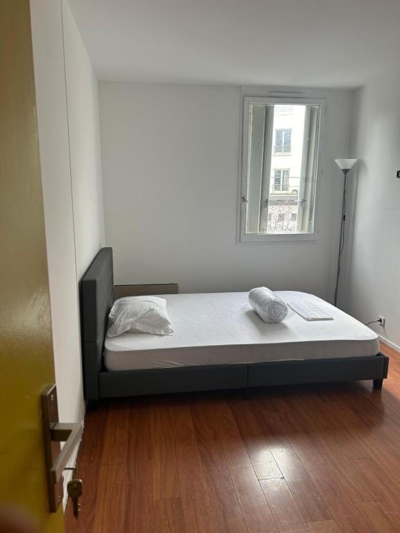 un lit assis dans une pièce avec une fenêtre dans l'établissement Agréable Chambre Confortable, à Asnières-sur-Seine