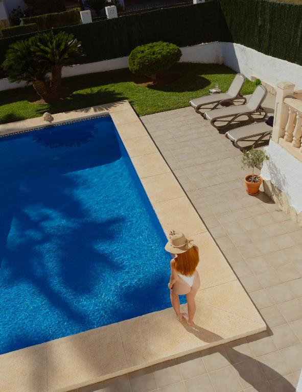 a woman in a hat standing next to a swimming pool at La Renda Mediterranean Villa - Beach, Jávea Port and amenities within walking distance in Jávea