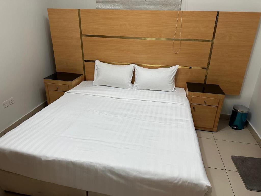 a bedroom with a large white bed with a wooden headboard at الميقات للشقق المخدومة - AL Miqat Serviced Apartments in Al Madinah