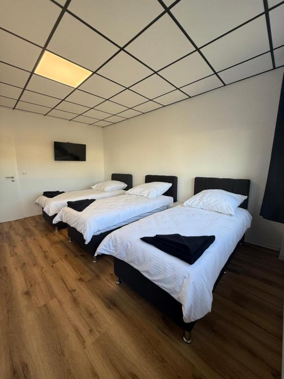 three beds in a room with wooden floors at ENSAS rooms in Koblenz