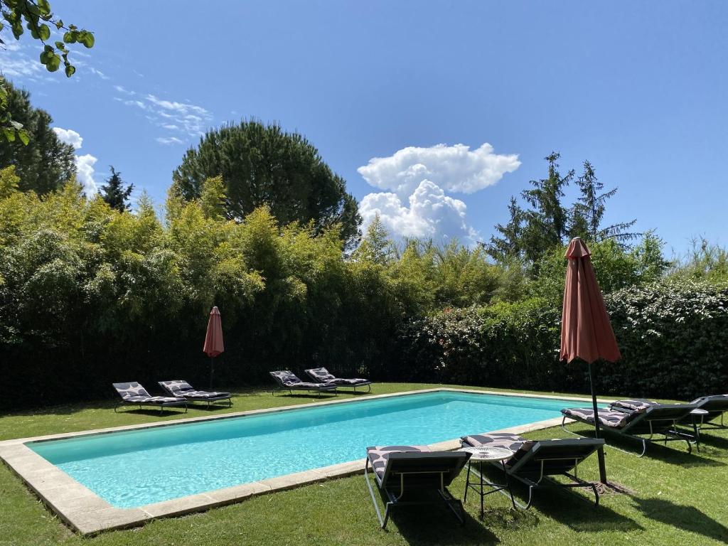 une piscine avec des chaises et un parasol dans l'établissement Mas la Pauline Gîtes de charme & roulotte, à Saint-Rémy-de-Provence