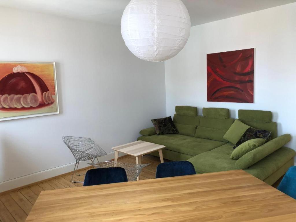 a living room with a green couch and a table at PRALINE in Colmar