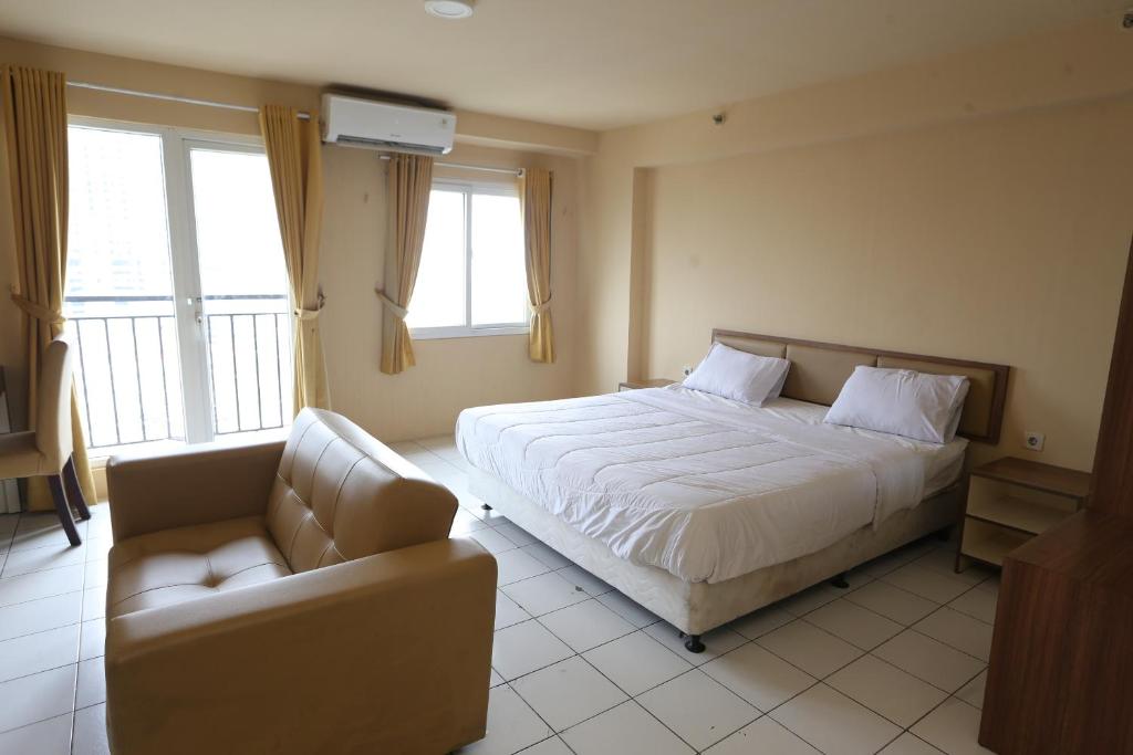 a bedroom with a bed and a couch and windows at Apartemen Mutiara Bekasi by Alfa Rooms in Pekayon Satu