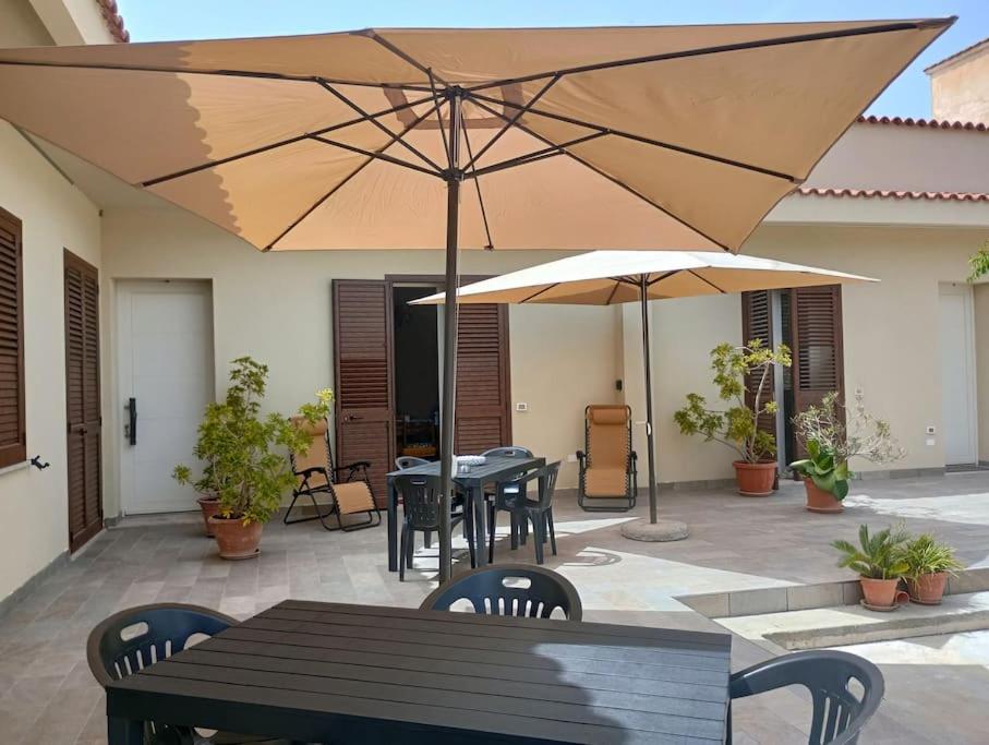 a patio with tables and chairs and umbrellas at West Sicily - Villa with Garden and Parking in Marsala