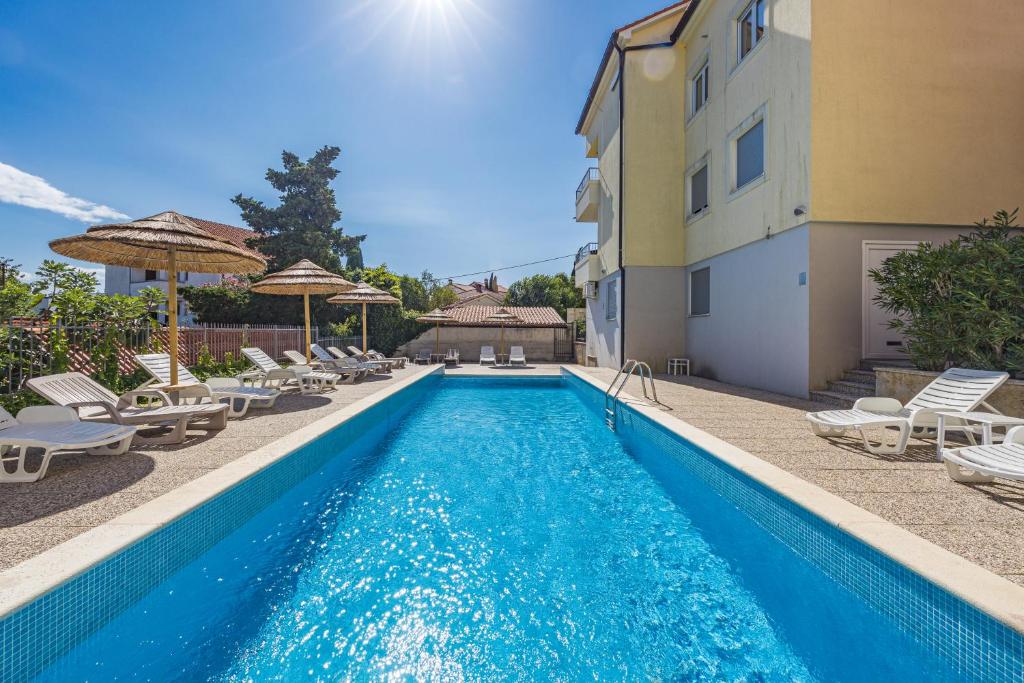 a swimming pool with lounge chairs and a building at Residence Kamenjak Center in Premantura