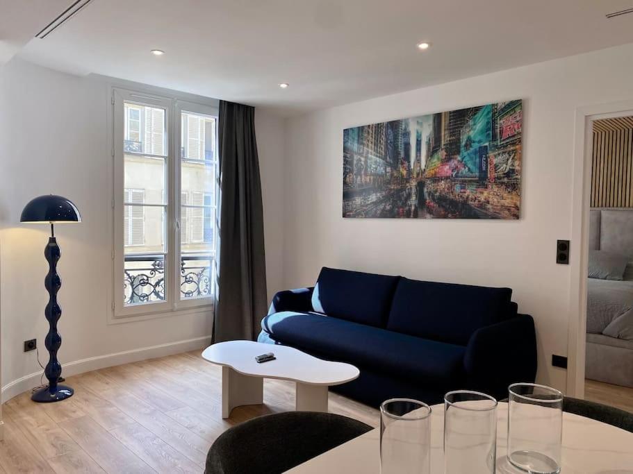 un salon avec un canapé bleu et une table dans l'établissement Renovated Apartment near Tuileries and Concorde, à Paris