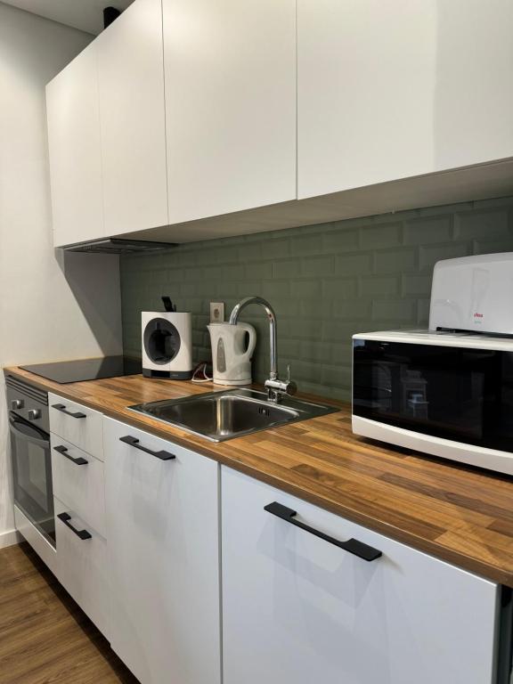a kitchen with white cabinets and a sink and a microwave at O Cantinho do Colégio - Dourocollege in Lamego