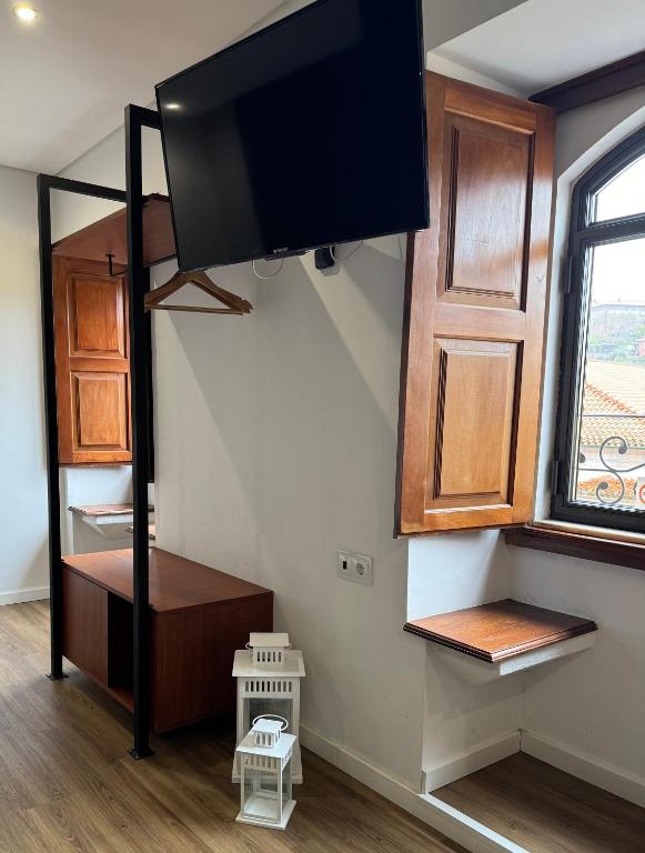 a living room with a tv on the wall and a staircase at O Cantinho do Colégio - Dourocollege in Lamego