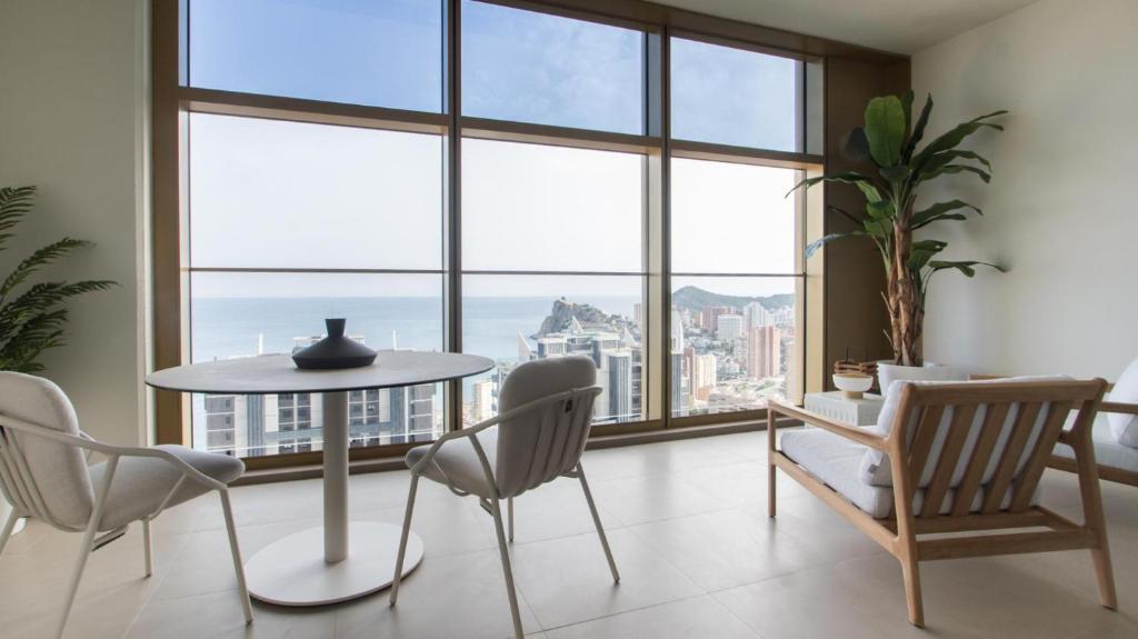 een eetkamer met een tafel, stoelen en ramen bij Intempo by Holuxe - 213 - 21st floor in Benidorm