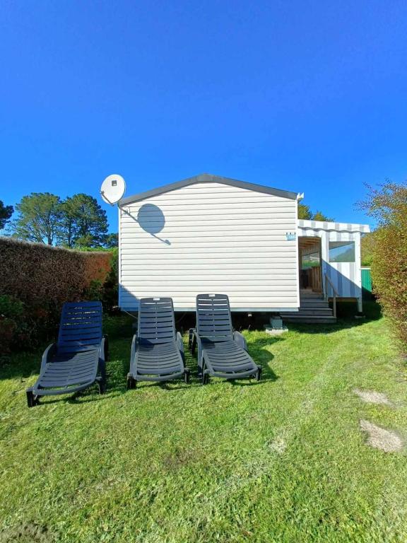 deux chaises de jardin et une maison avec caméra dans l'établissement Mobil home Luxueux - 40 m2 terrasse couverte - La Palmyre Les Mathes - Les Charmettes 4 étoiles, aux Mathes