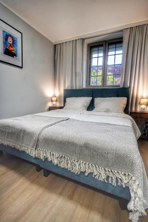a large bed in a bedroom with two windows at Happy Street OLD TOWN 24-hour Reception in Toruń