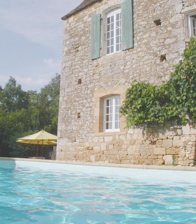 - un bâtiment en pierre avec une fenêtre et une piscine dans l'établissement Petite Mombette, à Cénac-et-Saint-Julien