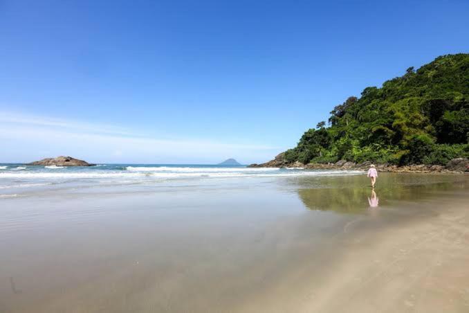 Un uomo che cammina su una spiaggia vicino all'oceano di Casa com localização privilegiada, a 140 metros da praia Juquey a São Sebastião