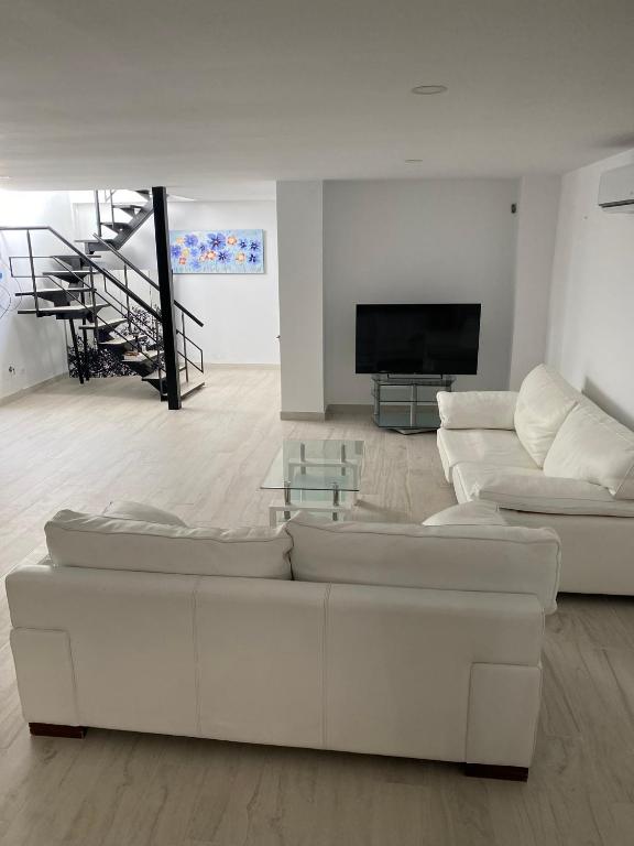 a living room with white furniture and a flat screen tv at New - MiJa basement Loft Apartment steps from Beach - perfect for Sun and Sport Seekers in Marbella