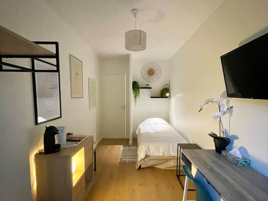 une chambre avec un lit et un bureau avec une télévision dans l'établissement Studio avec parking et terrasse, à Chartres