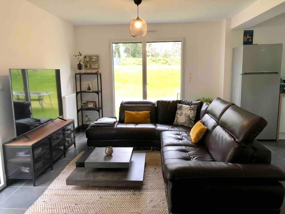 un salon avec un canapé en cuir et une table dans l'établissement Maison spacieuse et cosy- à 15 min des plages, à Quimper