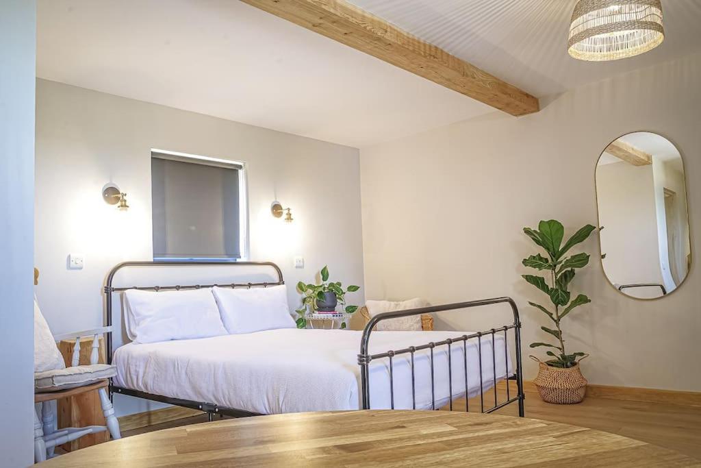 Un dormitorio con una cama, una mesa y un espejo. en Bryngwyn Guest Suite, en Camrose