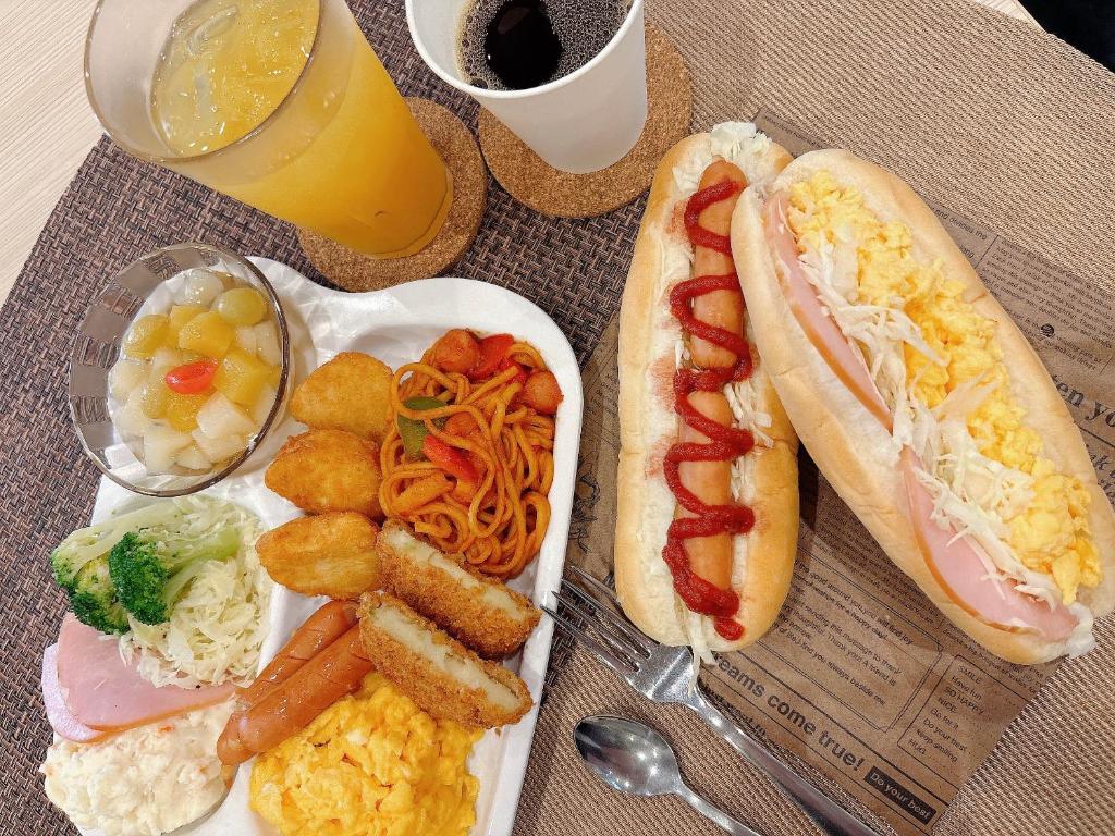 une table avec une assiette de nourriture avec un hot-dog et des pommes de terre dans l'établissement Hotel -ASIATO-, à Osaka