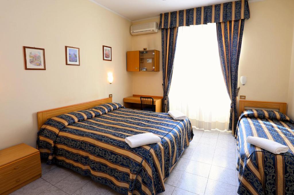 a hotel room with two beds and a window at Hotel Loreto in Milan