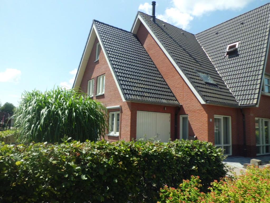uma casa de tijolos vermelhos com um telhado preto em Holiday home Jong em Schagerbrug