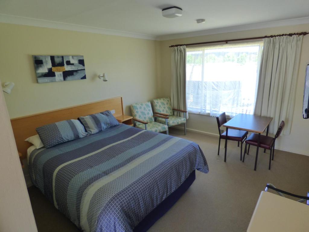 a bedroom with a bed and a table and a window at Anna Bella Motel Glen Innes in Glen Innes