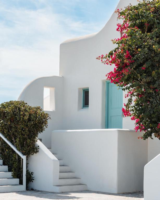 a white house with stairs and pink flowers at Ploes Seaside Houses in Plaka