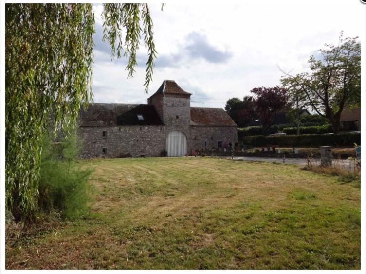 een oud stenen gebouw met een witte deur in een veld bij Le Gîte Du Prieuré in Namen