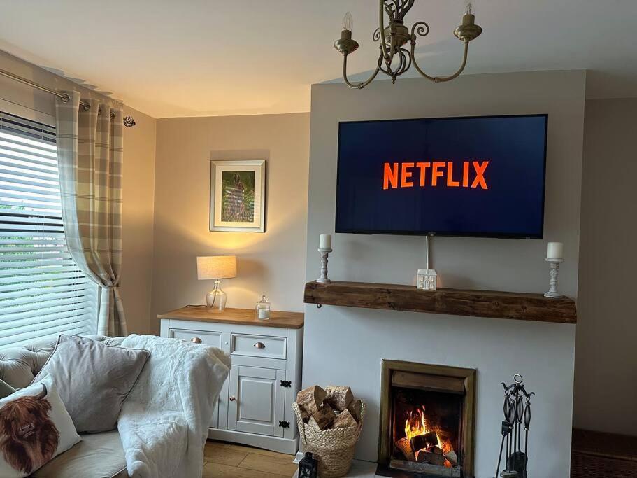 a living room with a television above a fireplace at Royal Hillsborough Hideaway in Hillsborough