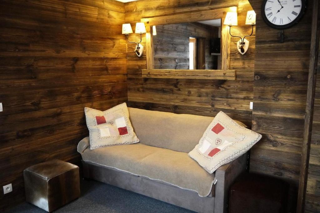 une chambre avec un canapé, un miroir et une horloge dans l'établissement Résidence Cembros - CEMBROS 31 MAE-6251, à Les Allues
