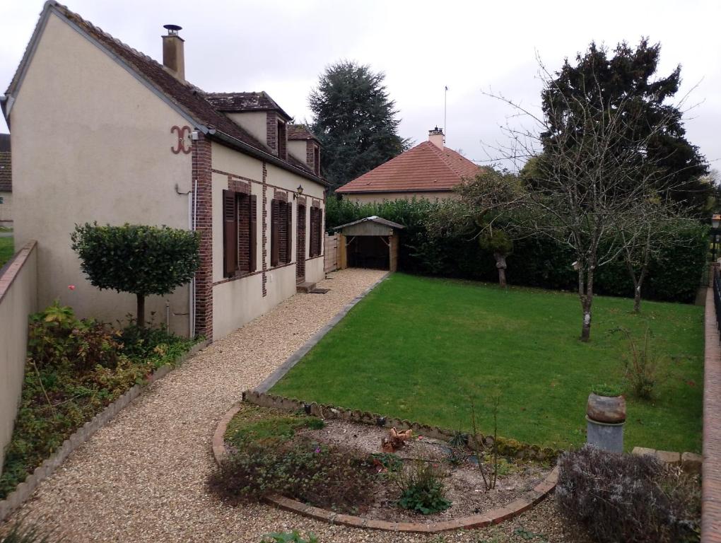 une arrière-cour d'une maison avec une pelouse dans l'établissement Longère au calme en ville, à Senonches