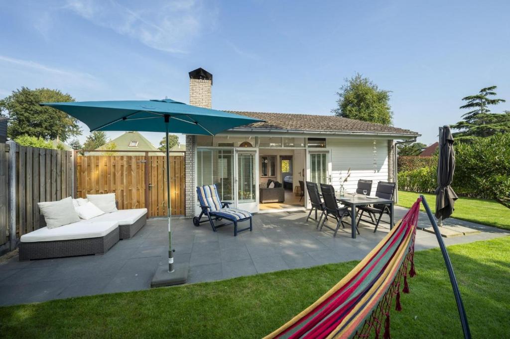 un patio con sofá y sombrilla en Toekomst 23 - Ouddorp - de Strandloper NOT INTENDED FOR COMPANY OR WORK-RELATED STAYS, en Ouddorp