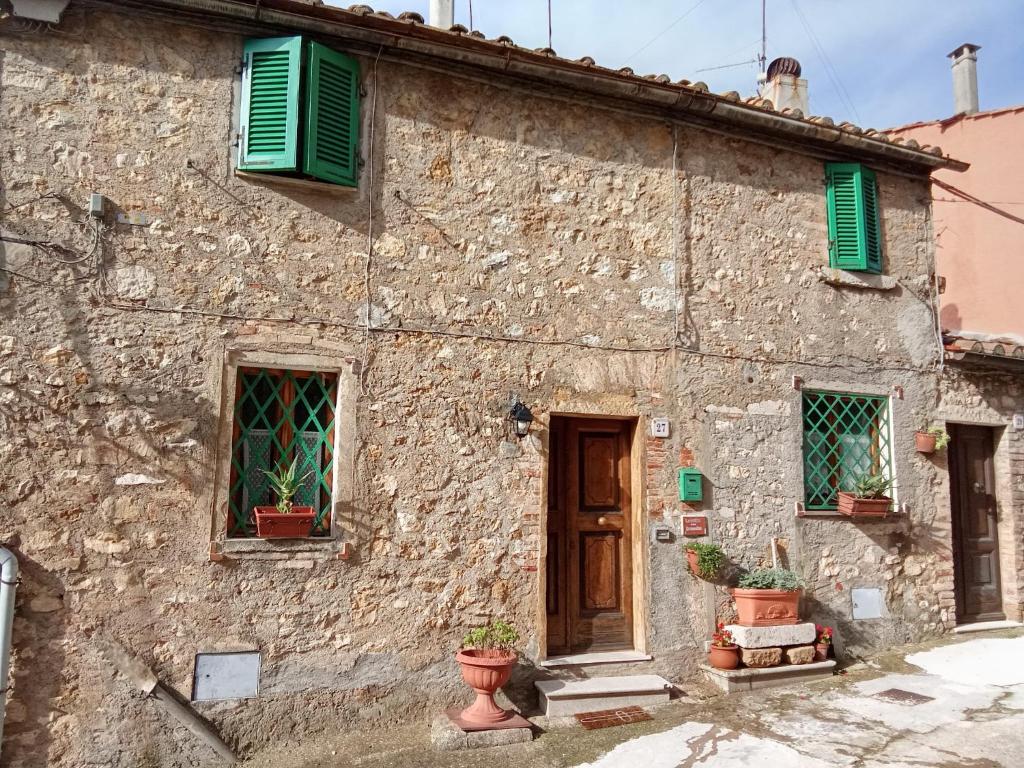 an old stone house with green shutters and potted plants at la casina della bubbolina in Semproniano