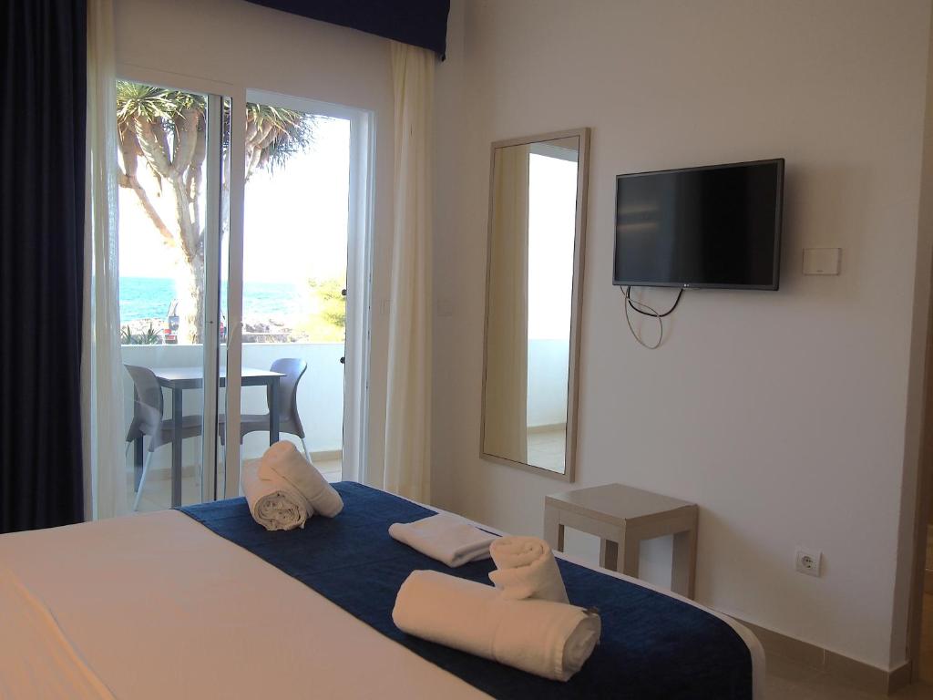 a bedroom with a bed with a tv on the wall at Hotel Roca Bella in Es Pujols