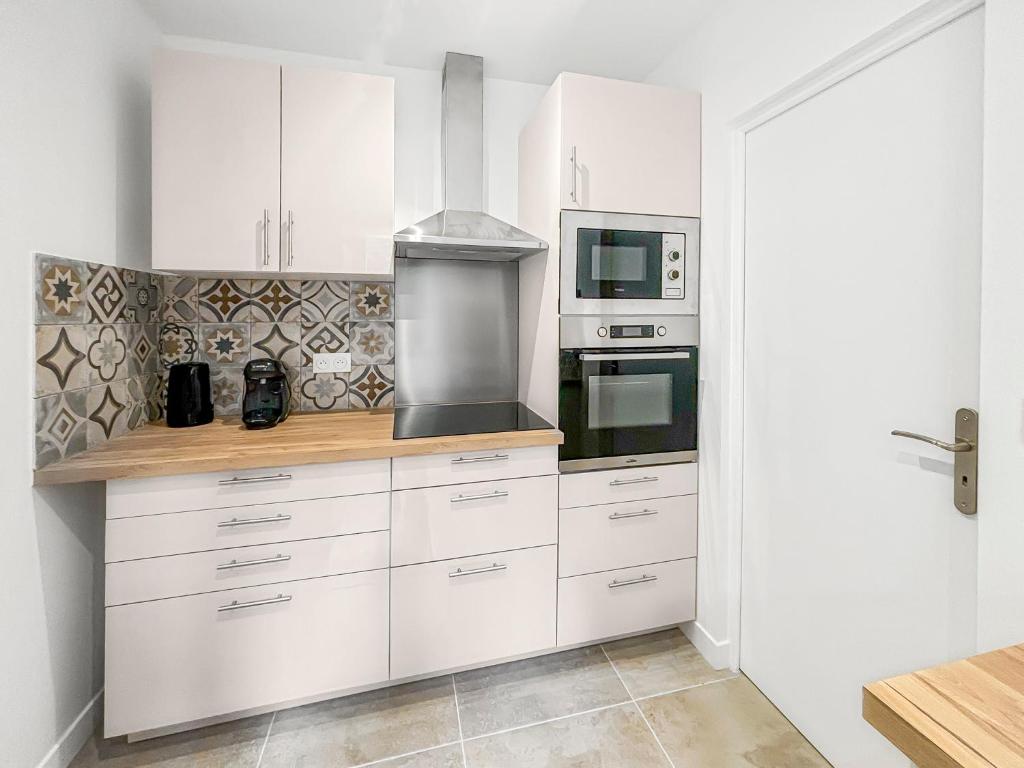 une cuisine avec des armoires blanches et une cuisinière dans l'établissement Charmante dépendance avec jardin partagé, à Eaubonne