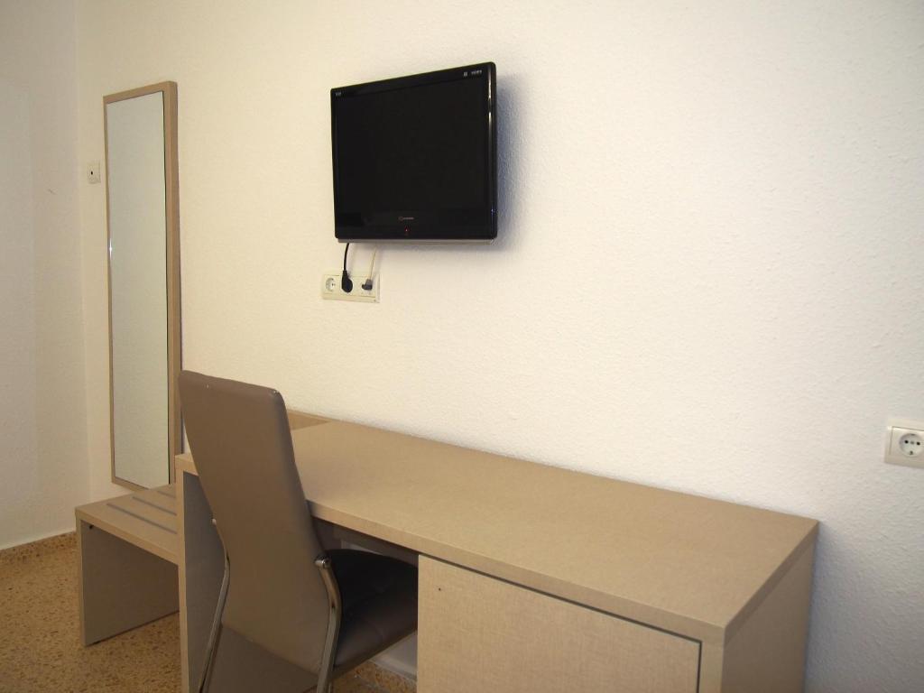 a room with a desk with a tv on the wall at Hotel Roca Bella in Es Pujols