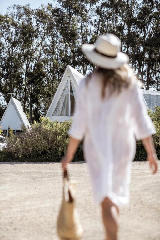 a young girl in a white dress and hat walking at Esperance Chalet Village in Esperance