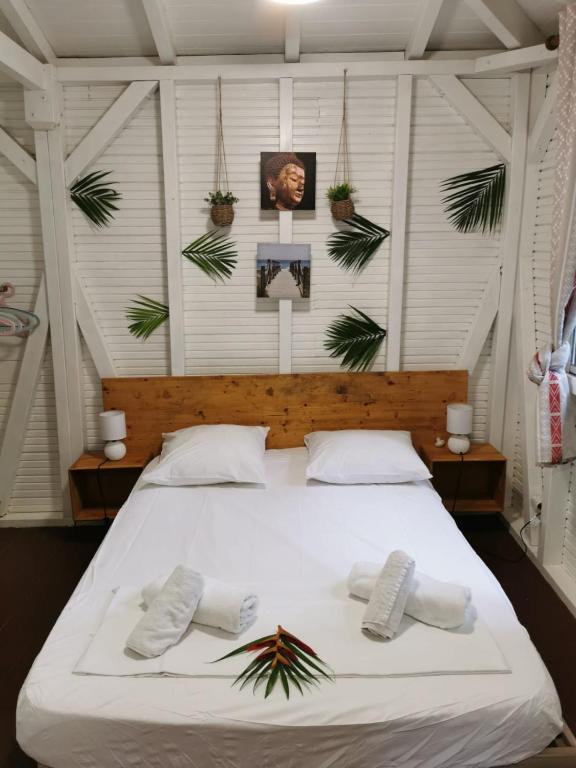 a bedroom with a large white bed with plants on the wall at Les Gîtes de la Lézarde in Petit-Bourg