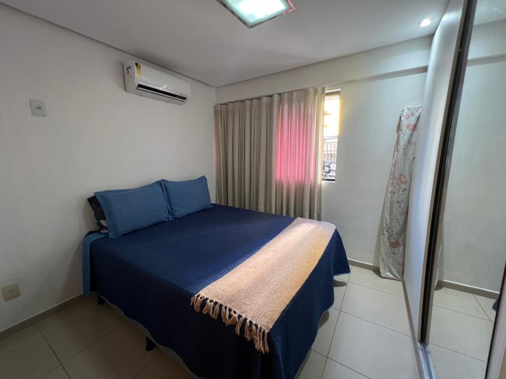 Un dormitorio con una cama azul y una ventana. en No melhor da Jatiuca, en Maceió