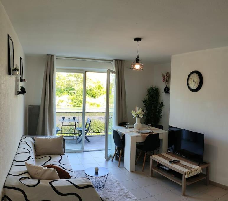 un salon avec un canapé, une table et un bureau dans l'établissement Charmant Appartement Cozy, à Saint-Jory